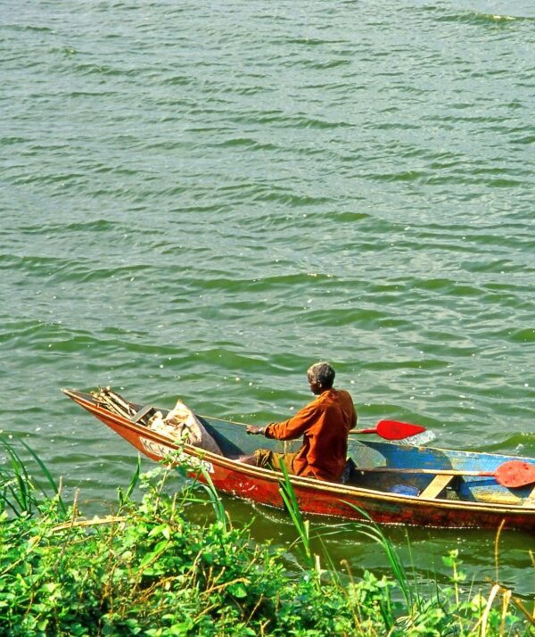 fishing on the Kazinga Channel in Uganda, surrounded by lush vegetation and calm waters, with hippos and birds in the background.