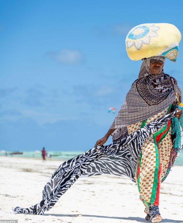 African woman in Zanzibar wearing a colorful traditional dress, walking through a historic Stone Town