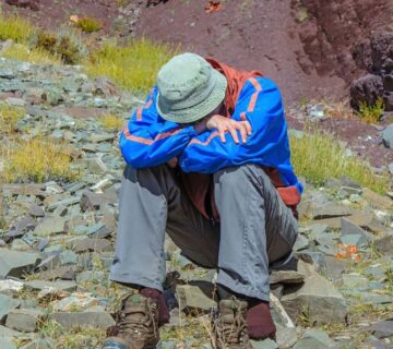 Person experiencing symptoms of altitude sickness while hiking at high altitude 