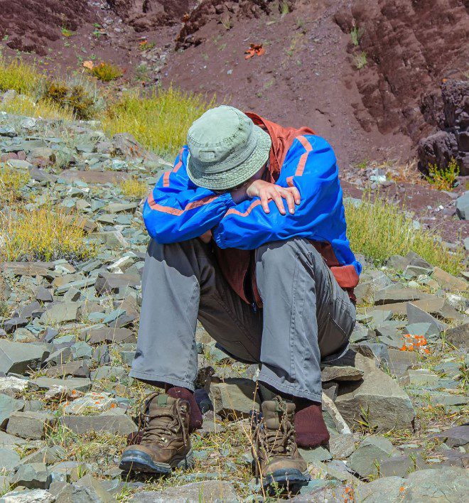 Person experiencing symptoms of altitude sickness while hiking at high altitude.