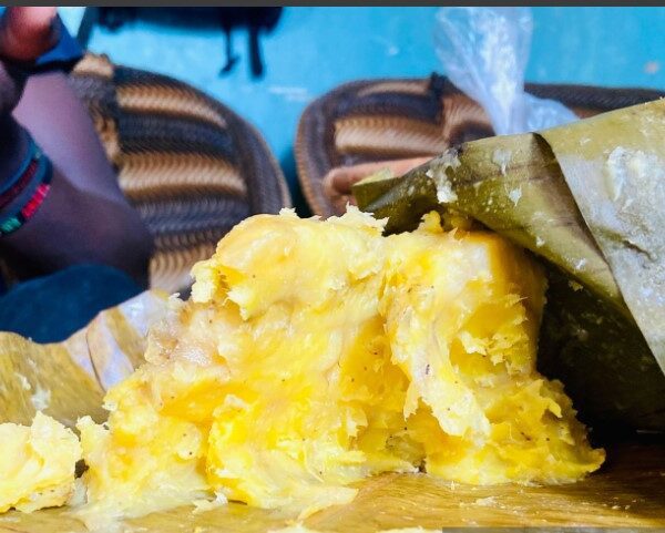 Traditional Ugandan matoke dish served with rich groundnut sauce on a banana leaf plate.