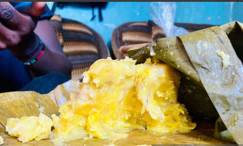 Traditional Ugandan matoke dish served with rich groundnut sauce on a banana leaf plate.