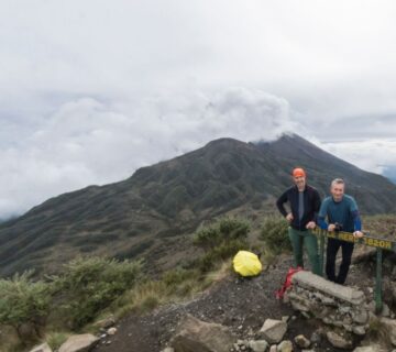 Hikers ascending Mount Meru with scenic mountain views in the background during a high altitude trekking adventure 