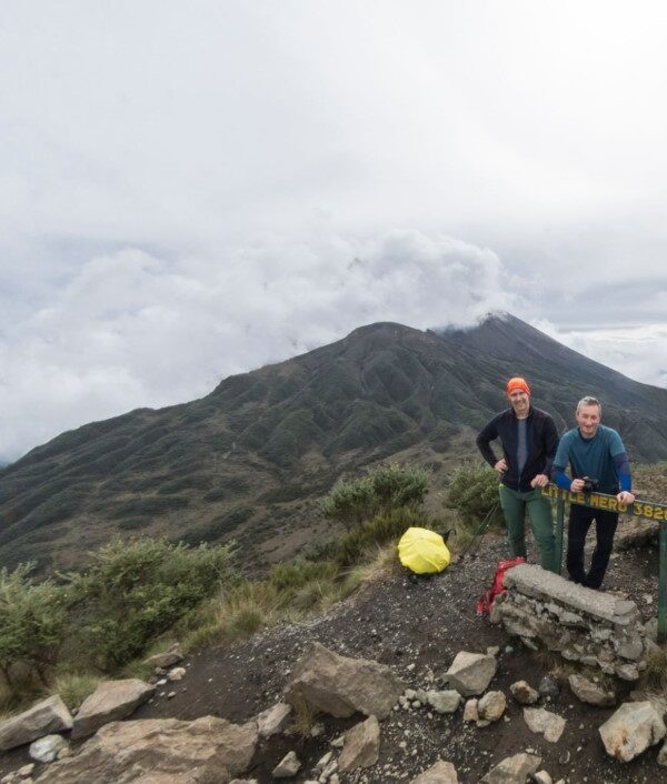 Hikers ascending Mount Meru with scenic mountain views in the background during a high-altitude trekking adventure.