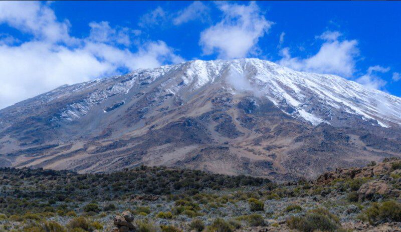 Mount Kilimanjaro towering above the African landscape, with its snow-capped summit and diverse ecosystems.