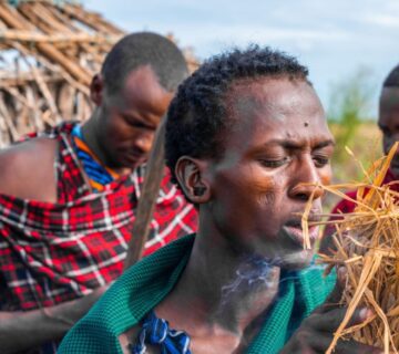 A traditional healer in Tanzania performing a spiritual ritual with fire, using herbs and cultural tools 