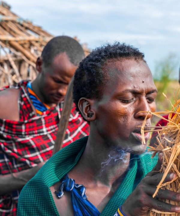 A traditional healer in Tanzania performing a spiritual ritual with fire, using herbs and cultural tools.