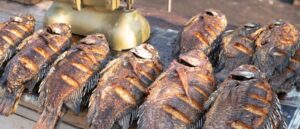 Smoked Ugandan fish, rich in flavor, served with vegetables and traditional sides.