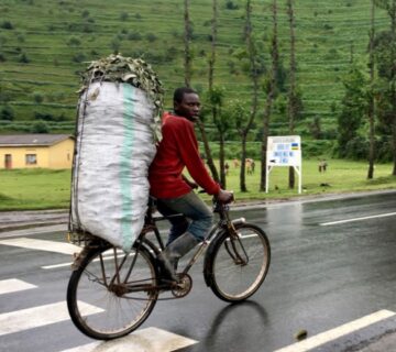 Cyclist riding through Rwanda’s lush green countryside with rolling hills in the background 