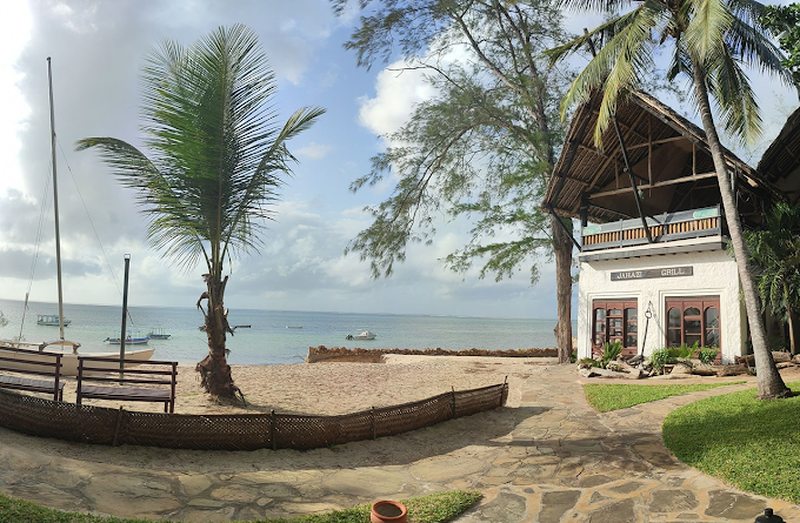 A palm fringed beach resort on Zanzibar with boats along the shore