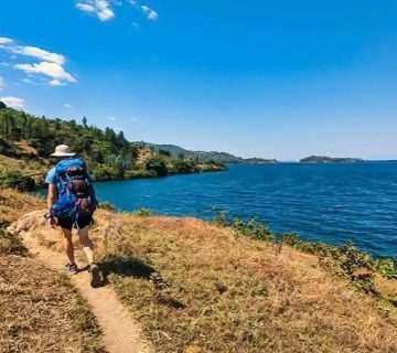 Hikers exploring a scenic hillside trail overlooking Lake Kivu along Rwanda's Congo Nile Trail 