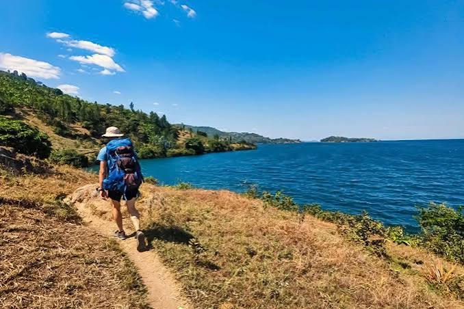 Hikers exploring a scenic hillside trail overlooking Lake Kivu along Rwanda's Congo Nile Trail