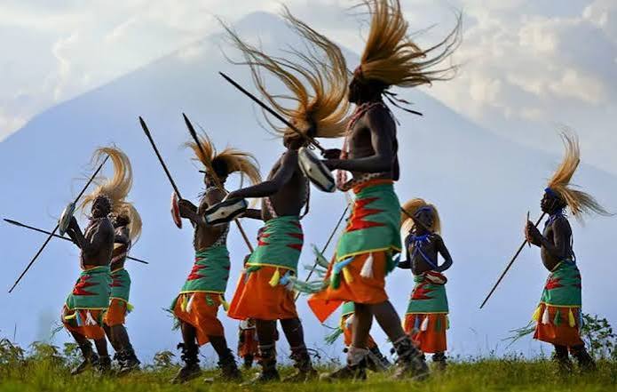 Traditional Intore dancers wearing flowing warrior headdresses and performing energetic movements during a cultural celebration in Rwanda