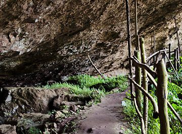 Enormous volcanic rock entrance to Musanze Caves surrounded by green vegetation in northern Rwanda 