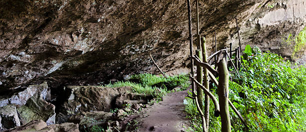 Enormous volcanic rock entrance to Musanze Caves surrounded by green vegetation in northern Rwanda