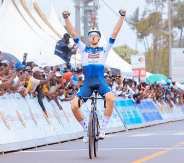 Professional cyclists competing in Tour du Rwanda along a scenic road surrounded by Rwanda's green hills 
