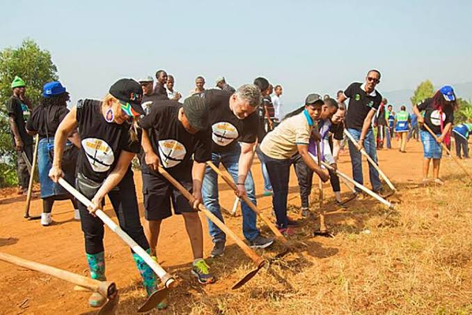 Residents participating in Umuganda community cleaning activities along a neighbourhood street in Kigali